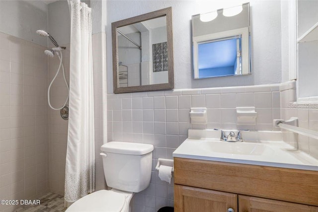 full bathroom with tile walls, a tile shower, vanity, and toilet