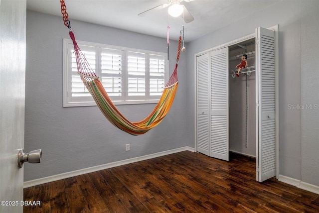 unfurnished bedroom with a closet, ceiling fan, baseboards, and wood finished floors