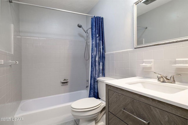 full bathroom featuring toilet, a wainscoted wall, shower / bath combo with shower curtain, vanity, and tile walls