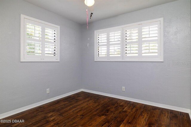 unfurnished room with baseboards and dark wood finished floors