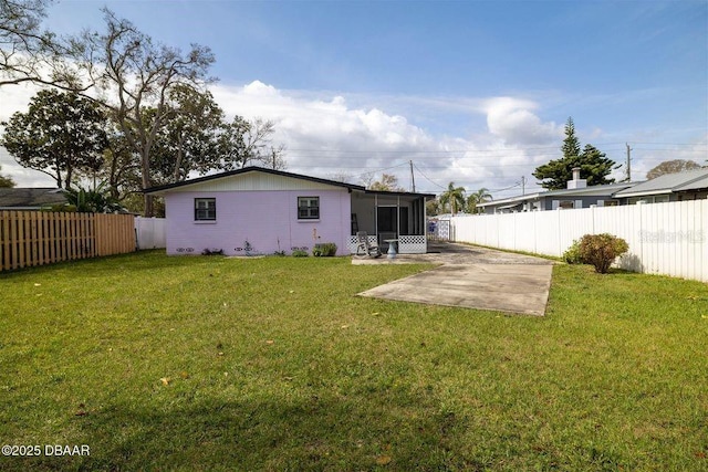 back of property with a patio area, a sunroom, a fenced backyard, and a lawn