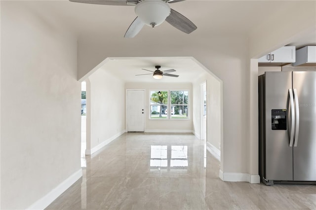 interior space with arched walkways, marble finish floor, stainless steel refrigerator with ice dispenser, white cabinetry, and baseboards