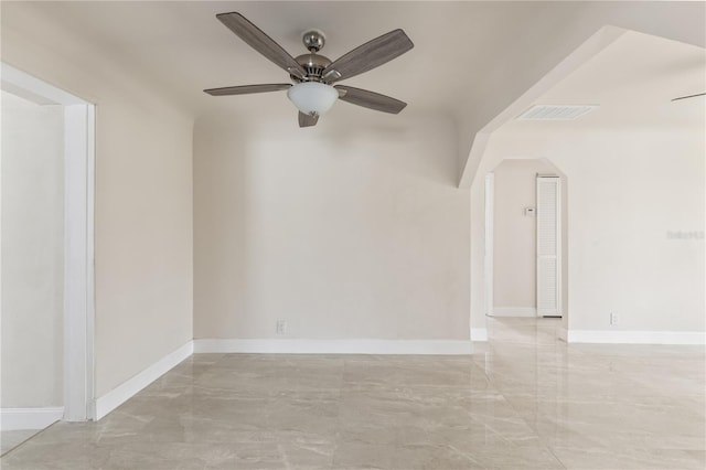 unfurnished room with arched walkways, ceiling fan, marble finish floor, and baseboards