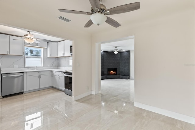 kitchen with visible vents, baseboards, light countertops, appliances with stainless steel finishes, and a brick fireplace