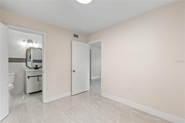 unfurnished bedroom with marble finish floor, visible vents, ensuite bath, and baseboards