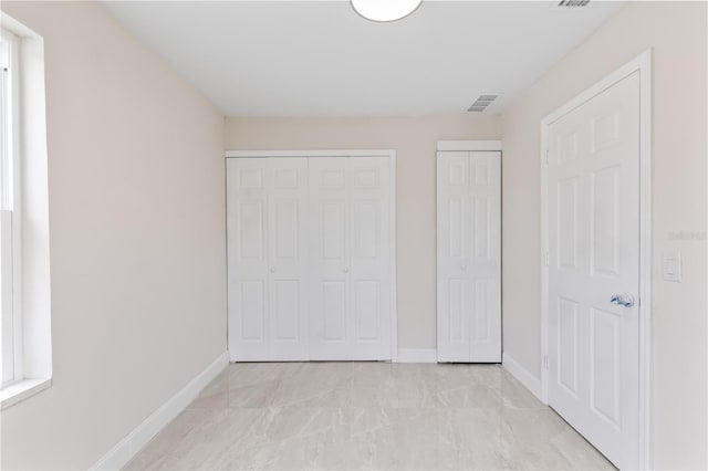 unfurnished bedroom with visible vents, baseboards, and multiple closets