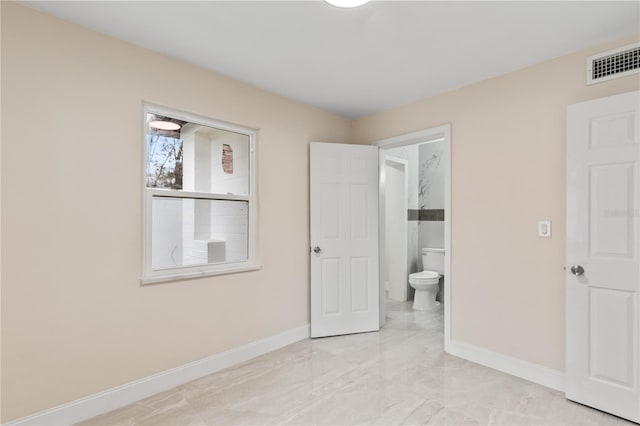 unfurnished bedroom with visible vents, baseboards, and ensuite bathroom