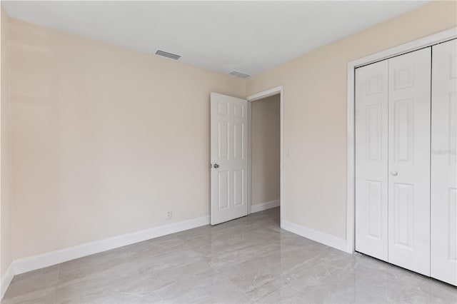 unfurnished bedroom with marble finish floor, a closet, visible vents, and baseboards