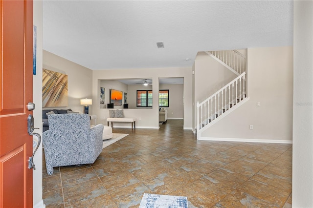 foyer featuring visible vents, a ceiling fan, stairs, and baseboards