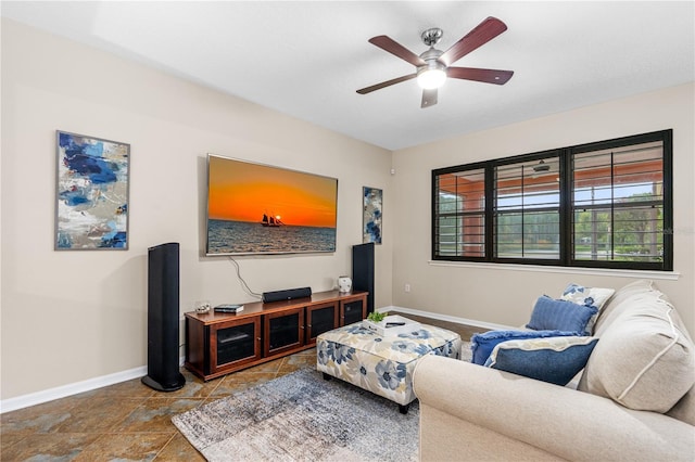 living area with baseboards and a ceiling fan