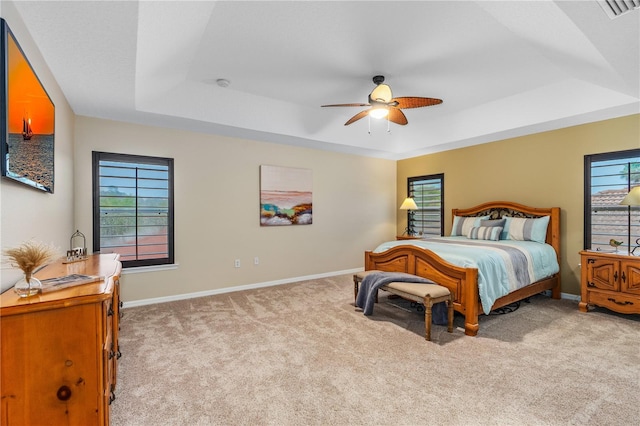 bedroom featuring carpet flooring, multiple windows, baseboards, and a tray ceiling