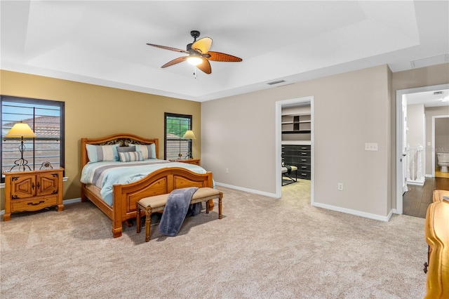 carpeted bedroom featuring visible vents, a raised ceiling, and baseboards