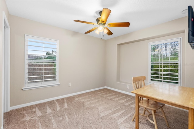 unfurnished office with carpet flooring, a healthy amount of sunlight, baseboards, and a ceiling fan