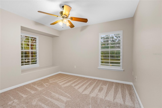 carpeted spare room with a ceiling fan and baseboards