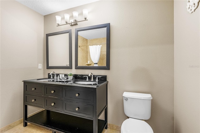 bathroom featuring a sink, baseboards, toilet, and double vanity