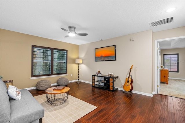 living area with visible vents, baseboards, wood finished floors, and a ceiling fan