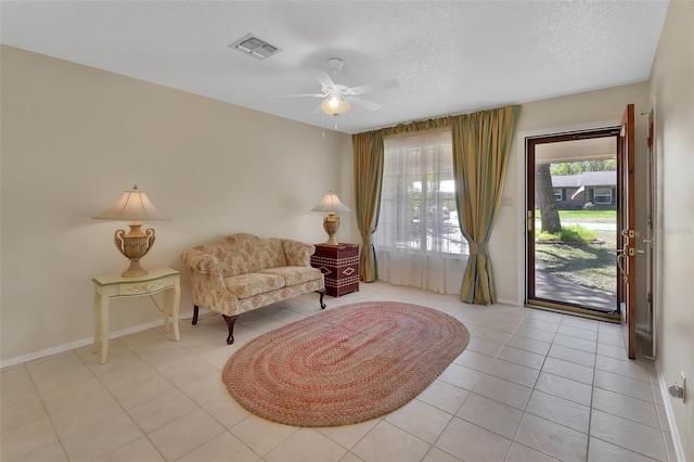 sitting room with light tile patterned floors, visible vents, ceiling fan, a textured ceiling, and baseboards