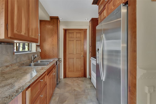 kitchen featuring light tile patterned floors, stainless steel fridge, white electric stove, brown cabinetry, and a sink