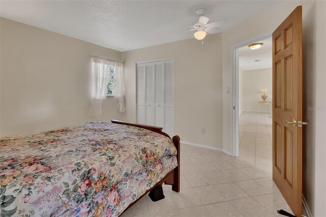 bedroom with a ceiling fan, baseboards, a closet, and light tile patterned flooring