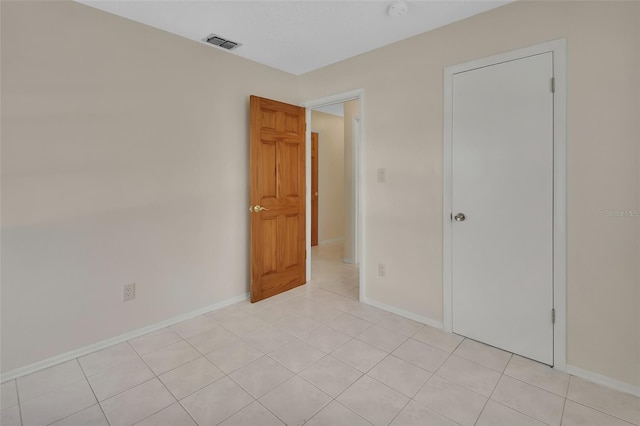 spare room featuring light tile patterned floors, visible vents, and baseboards