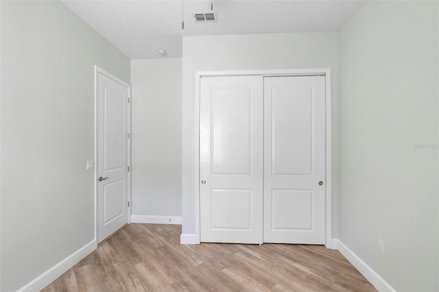 unfurnished bedroom with baseboards, a closet, visible vents, and light wood-style floors