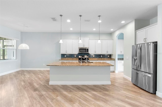 kitchen featuring arched walkways, visible vents, appliances with stainless steel finishes, light wood-type flooring, and tasteful backsplash