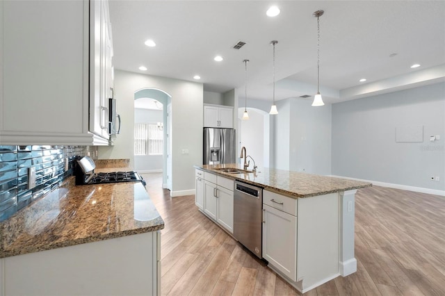 kitchen featuring arched walkways, light wood-style flooring, stainless steel appliances, a sink, and visible vents