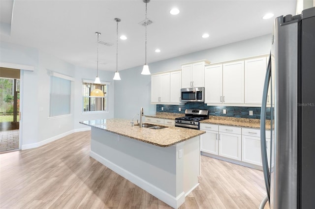 kitchen featuring tasteful backsplash, light wood-style flooring, appliances with stainless steel finishes, white cabinets, and a sink