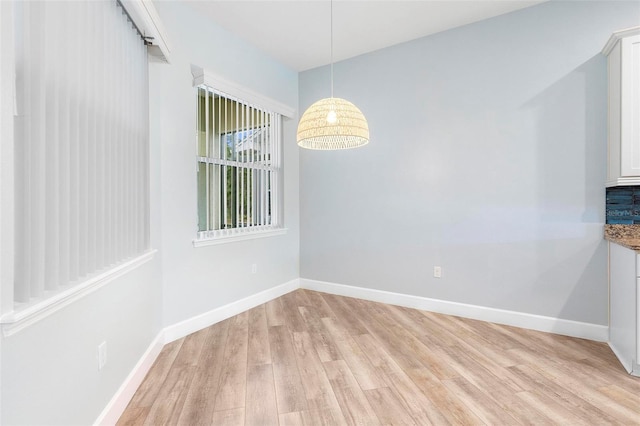 unfurnished dining area featuring light wood-style floors and baseboards