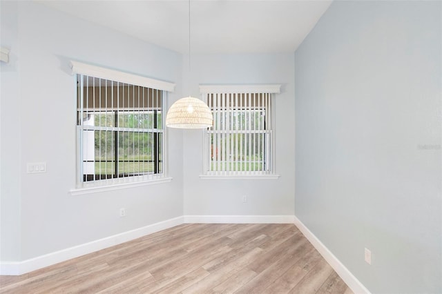 unfurnished room featuring a healthy amount of sunlight, baseboards, and wood finished floors