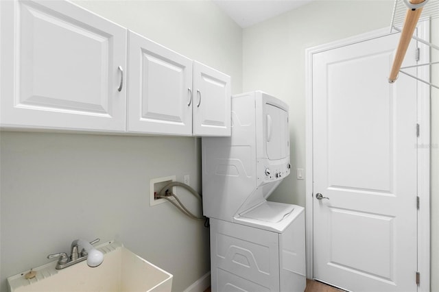 washroom featuring stacked washer and dryer and cabinet space