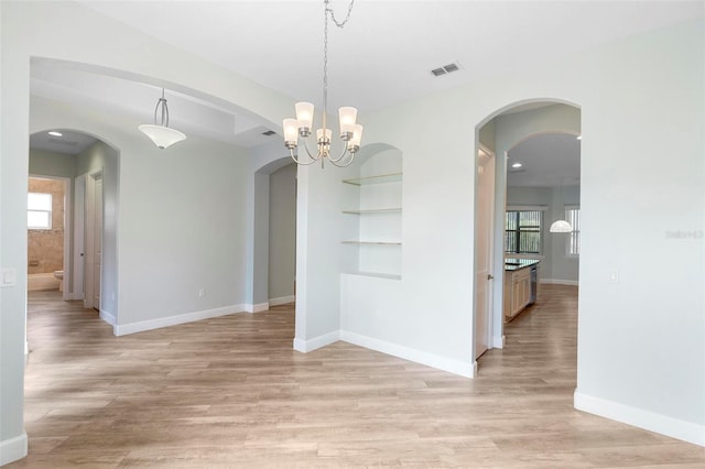 unfurnished dining area featuring a notable chandelier, light wood-type flooring, visible vents, and baseboards