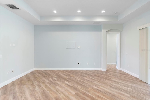 empty room featuring light wood-type flooring, visible vents, baseboards, and recessed lighting