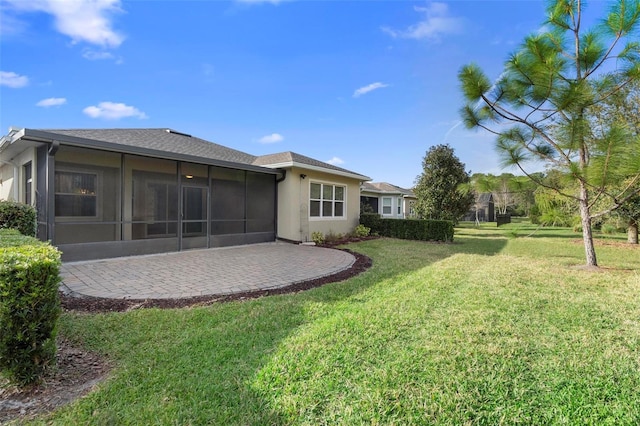 rear view of house with a sunroom, a patio area, and a yard