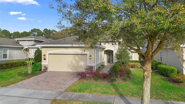 view of front of property featuring an attached garage, decorative driveway, a front yard, and stucco siding