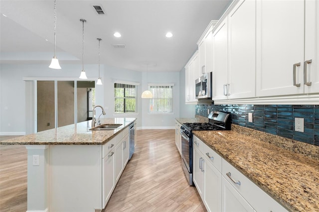 kitchen with a sink, visible vents, light wood-style floors, appliances with stainless steel finishes, and tasteful backsplash