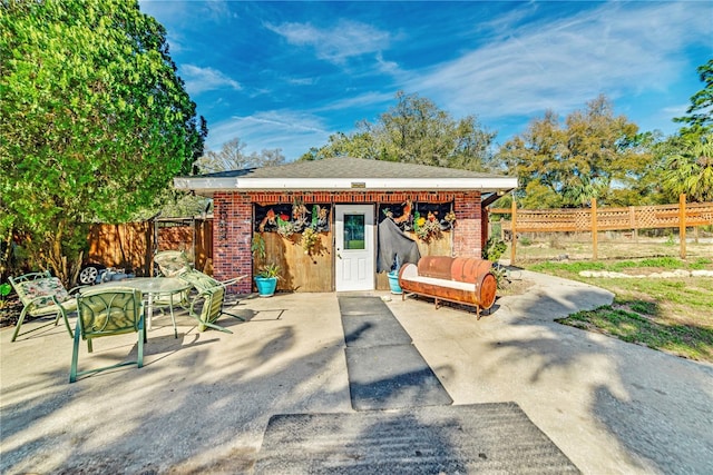 view of patio with an outbuilding, outdoor dining space, and fence