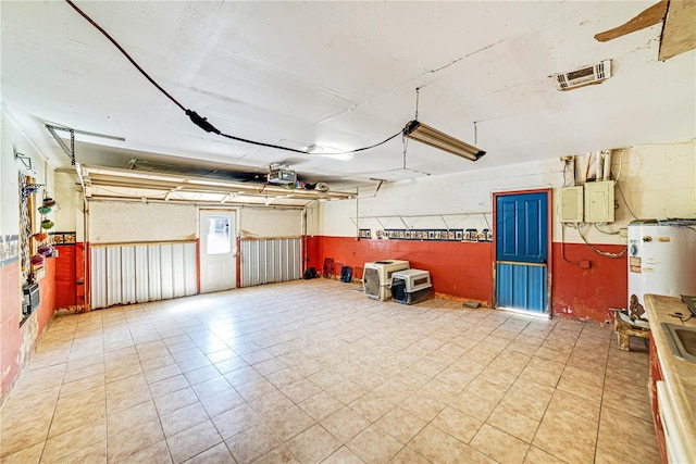 garage featuring concrete block wall, electric panel, visible vents, a garage door opener, and water heater