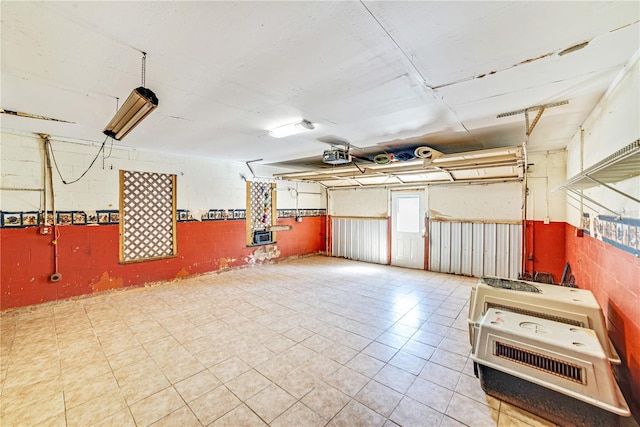 garage featuring wainscoting, concrete block wall, and a garage door opener