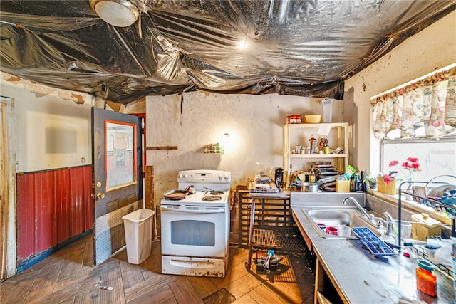 kitchen with wainscoting, a sink, and white range with electric cooktop