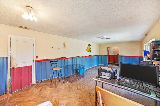 interior space featuring a textured ceiling, wainscoting, and visible vents