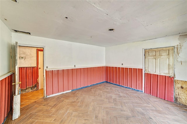 unfurnished room with a wainscoted wall and wood walls