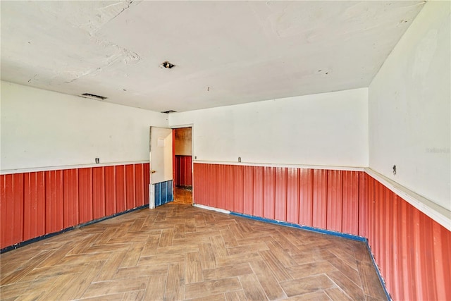 unfurnished room featuring wainscoting and wood walls