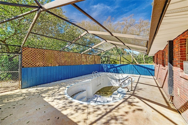 view of swimming pool featuring glass enclosure and a patio