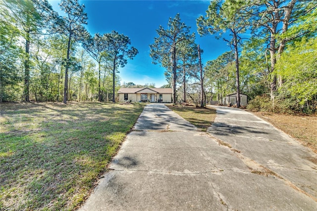 view of front facade with driveway, an outdoor structure, and a front yard