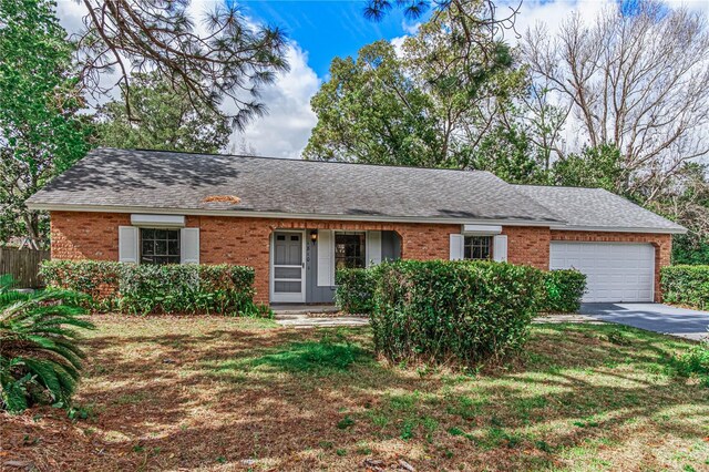 single story home featuring an attached garage, a shingled roof, concrete driveway, and brick siding