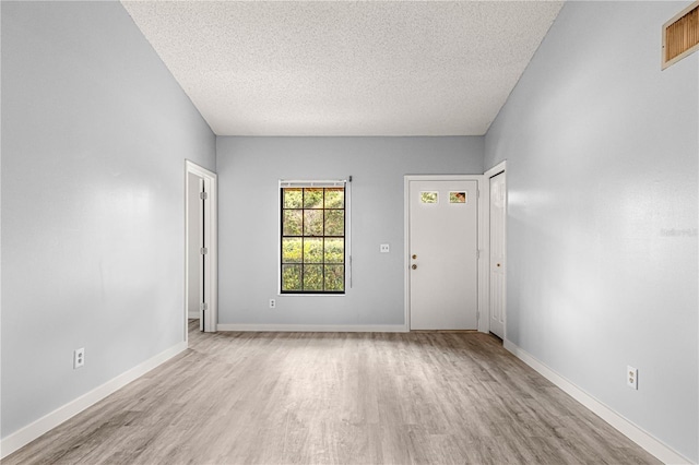 interior space featuring a textured ceiling, wood finished floors, visible vents, and baseboards