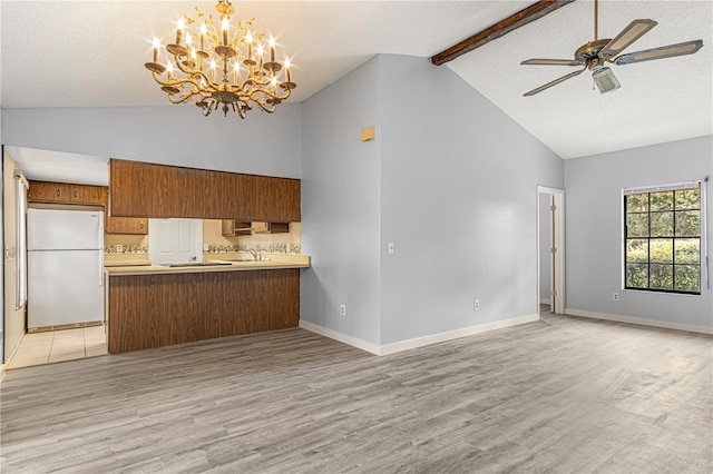 kitchen with brown cabinetry, freestanding refrigerator, open floor plan, and a peninsula