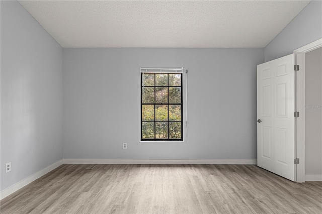 empty room with light wood-type flooring, a textured ceiling, and baseboards