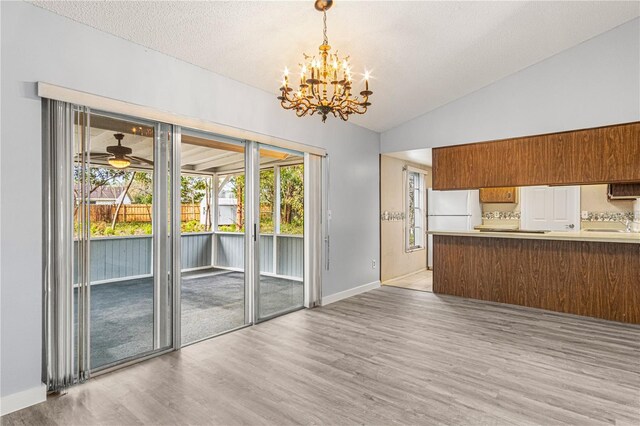 interior space featuring vaulted ceiling, brown cabinetry, wood finished floors, and freestanding refrigerator